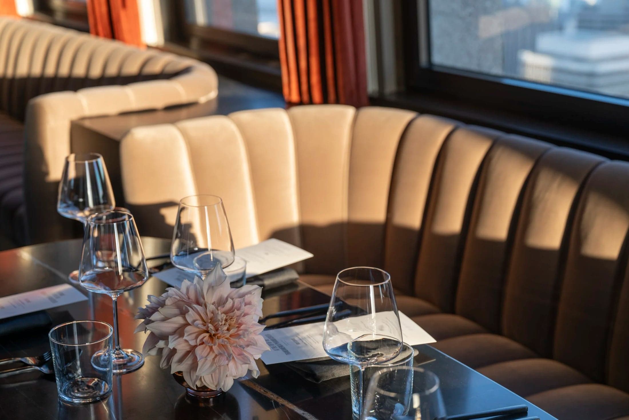 Glassware and flowers on a table beside upholstered seating at Sky Bar.