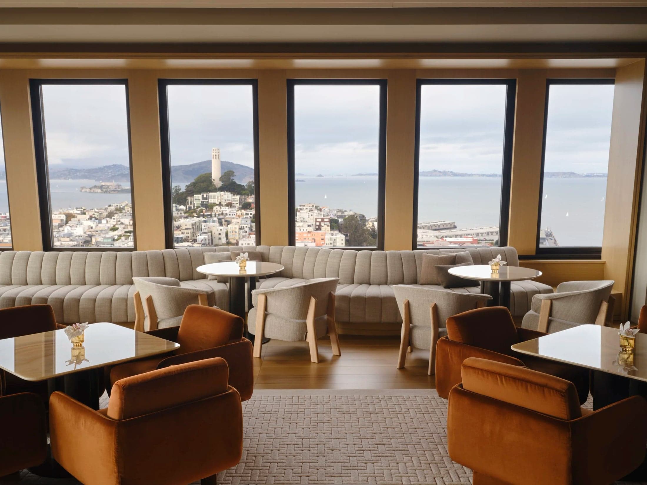 Small tables and armchairs beside Bay Lounge’s bay-facing windows.