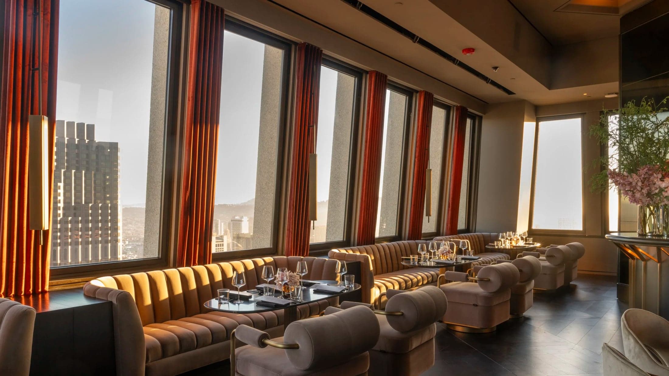 Tables and upholstered chairs beside Sky Bar’s windows overlooking the city.